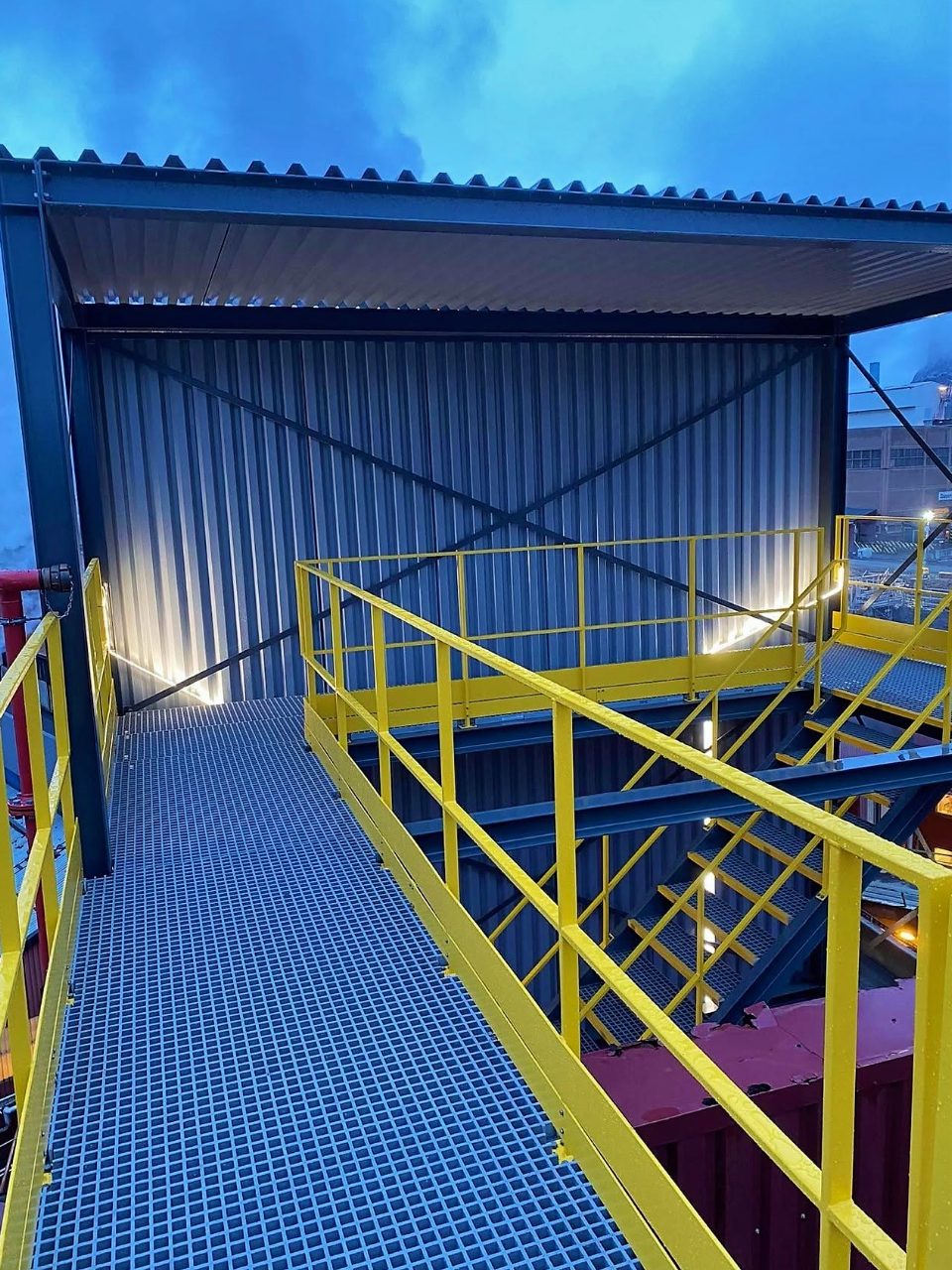 Steel platform with yellow handrails and grated walkway at dusk